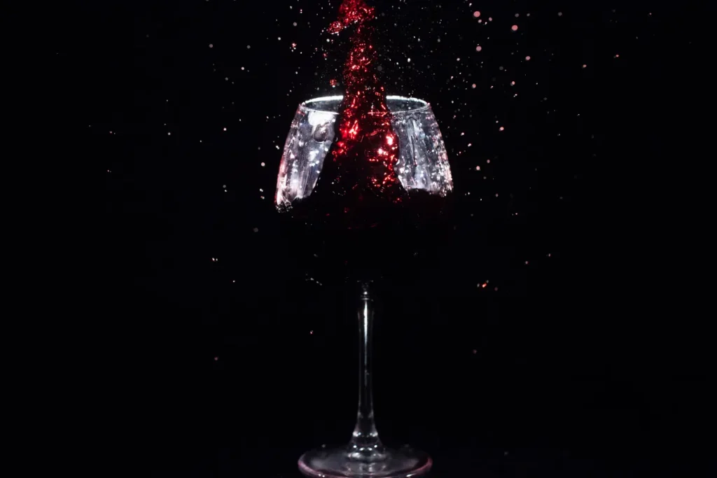 Copa de vino tinto salpicando sobre fondo negro